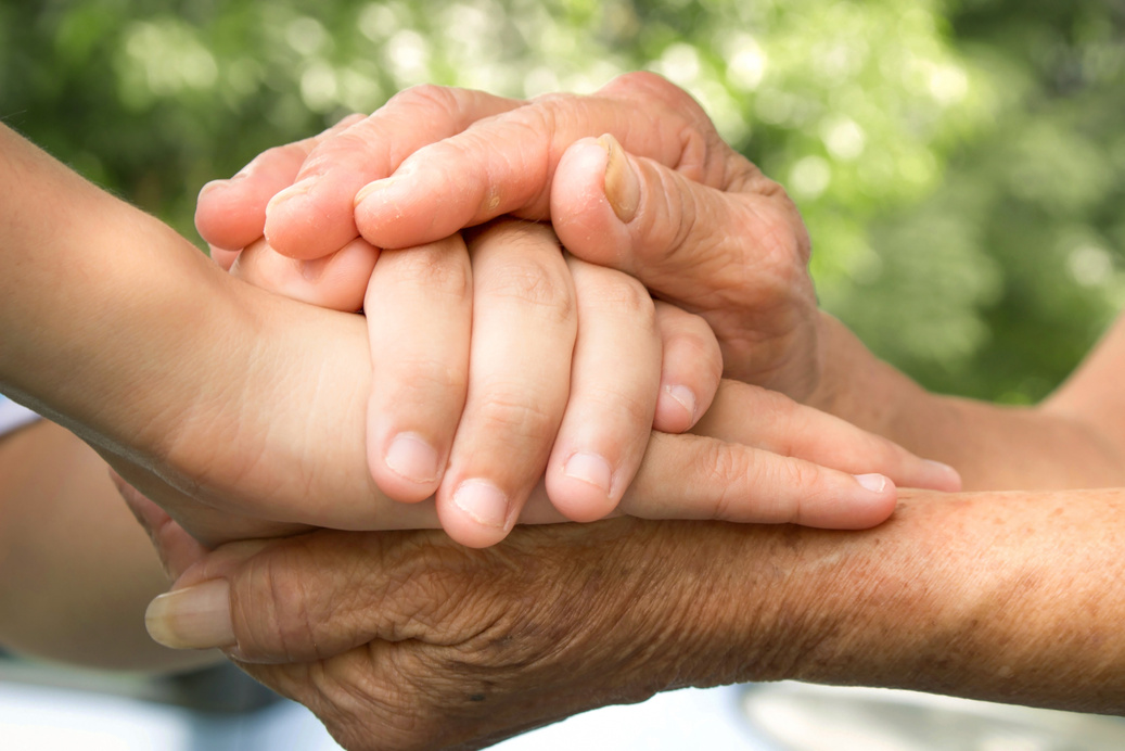International Day of Families concept: carer hand holding elder hand in hospice care